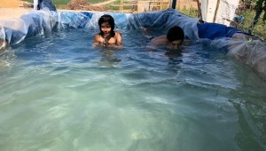 Köyün çocukları brandadan yapılan havuzda serinliyor