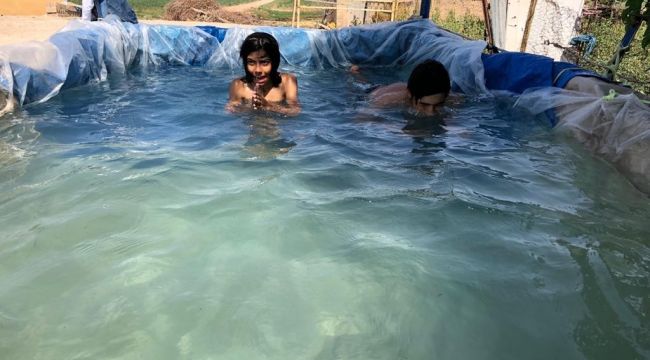 Köyün çocukları brandadan yapılan havuzda serinliyor